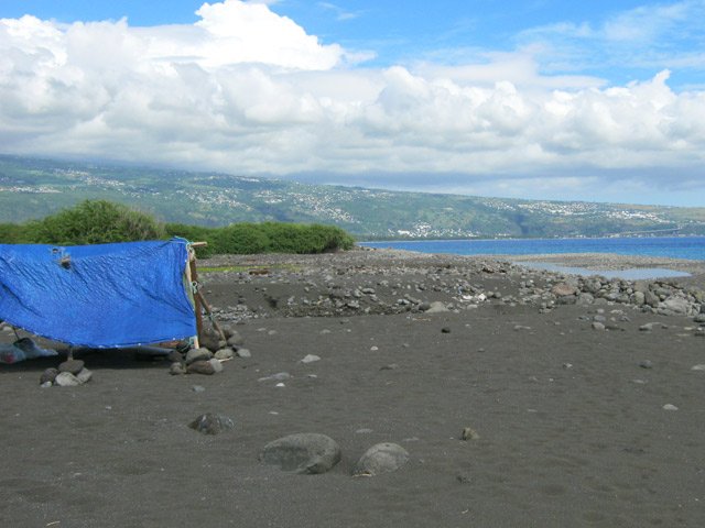 Quelques galets dépassent du sable gris de la plage autour de l'estuaire