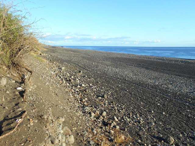 Le petit sentier dans les galets le long de la plage grise du Port